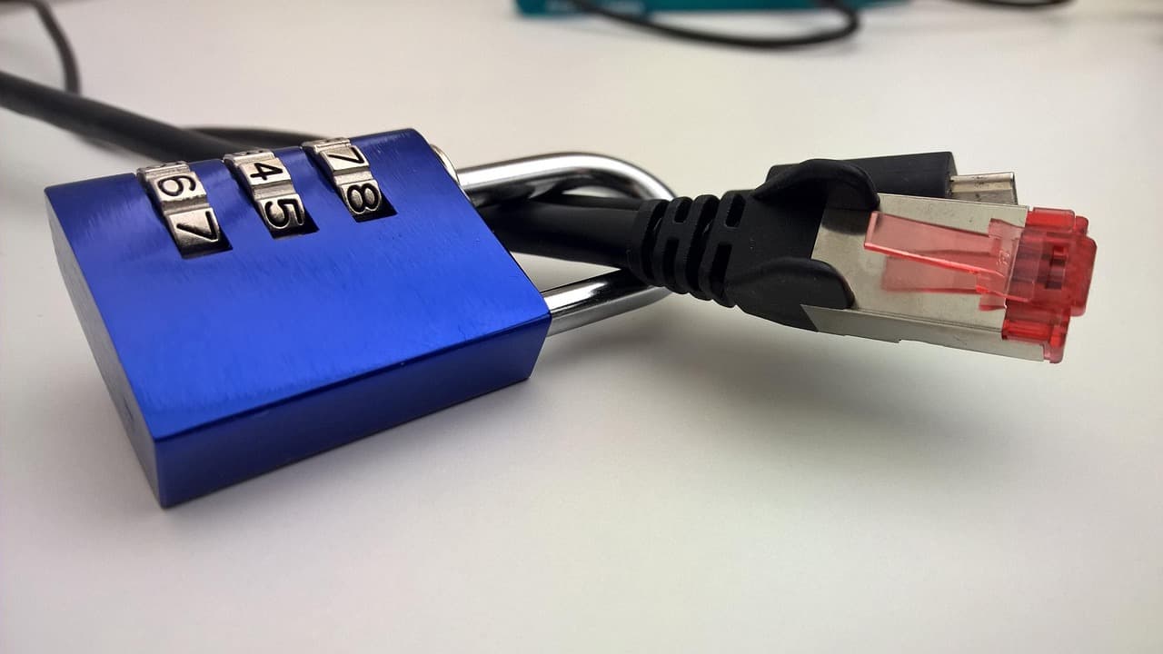 A blue combination padlock locked around a network Ethernet cable