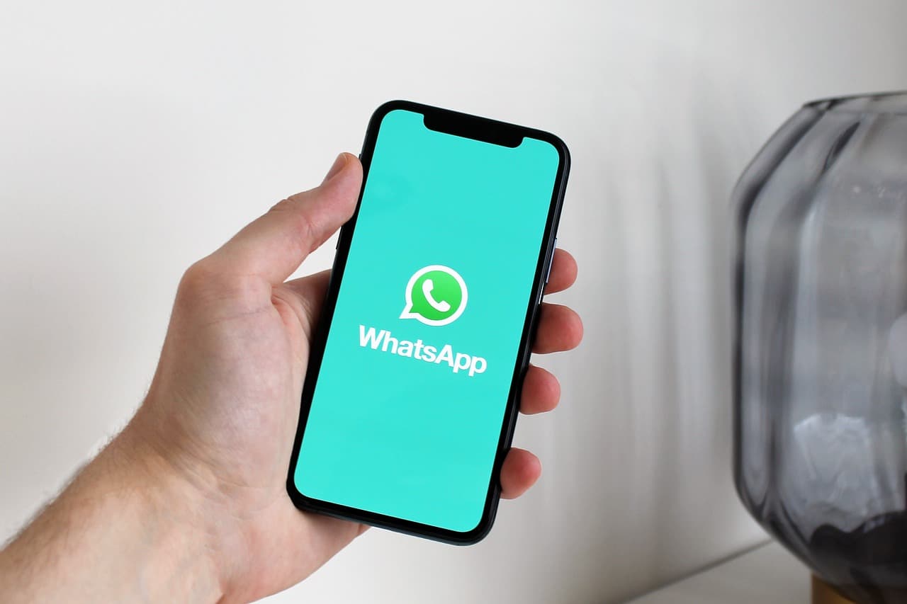 A hand holding a smartphone displaying the WhatsApp messaging app