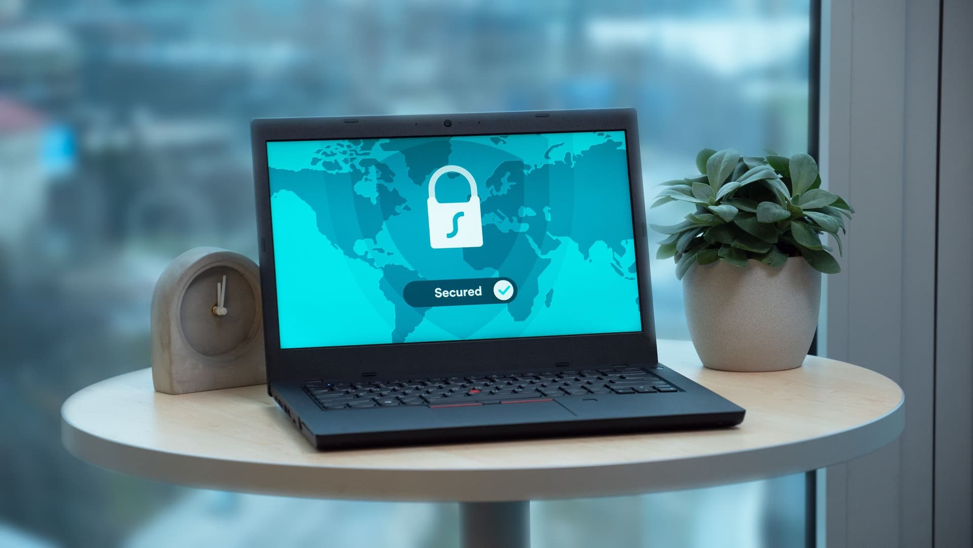 A laptop on a table showing a padlock icon over a world map with a 'Secured' label - reassuring UI, but the real question is who holds the encryption keys.