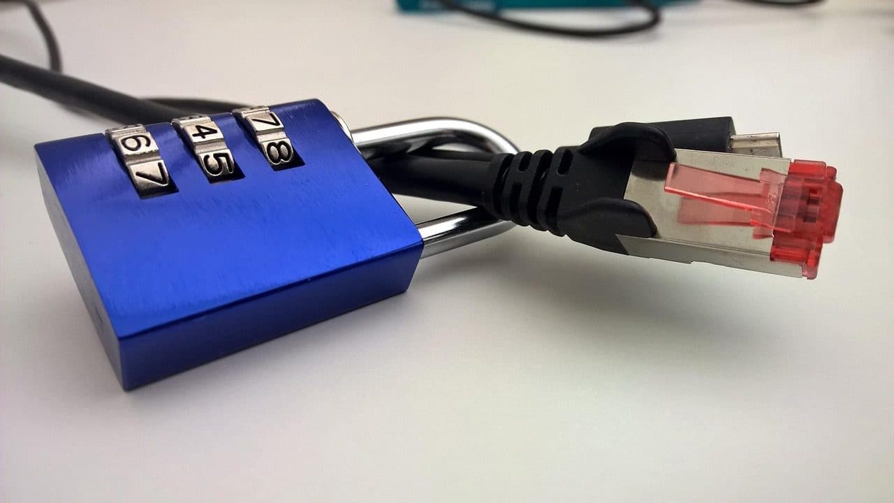 A blue combination padlock attached to an Ethernet network cable on a desk